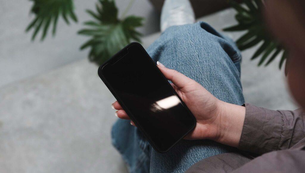 sitzend mit Telefon auf dem Schoß