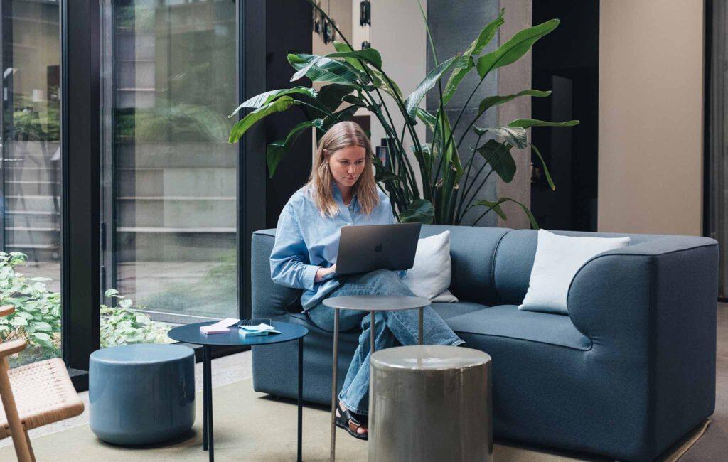 woman sitting with working computer on sofa